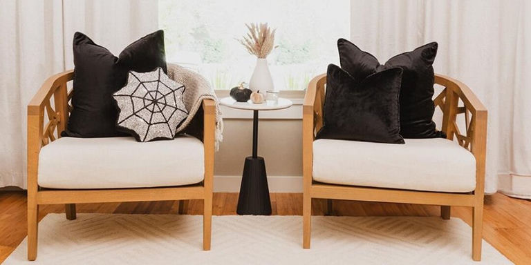 almohadas de terciopelo y rhinestones estilizadas en sillas de madera en un rincón de lectura