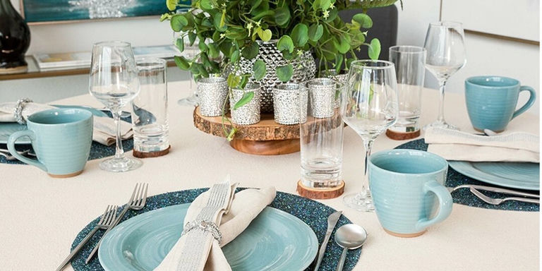 Neutral tablescape with greenery centerpiece, crystal votives, and blue ceramic dinnerware