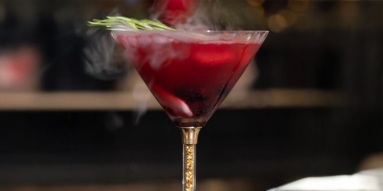 smoky blackberry Halloween cocktail in rhinestone martini glass with rosemary garnish
