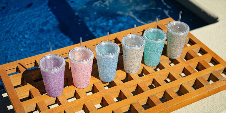 Collection of rhinestone glam tumblers in pastel colors on wooden pool tray