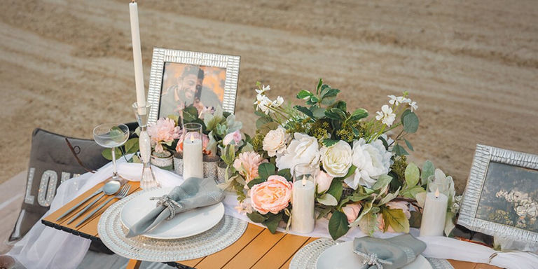 Configuración de mesa glamorosa frente al mar con cargadores de diamantes de imitación y flores