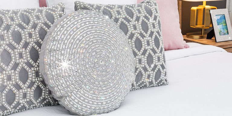 cojín redondo gatsby de strass estilizado con cojines de strass geométricos en una cama glamurosa blanca