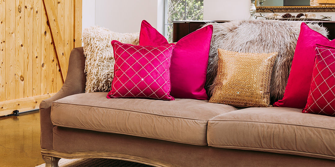 Layered&amp;&#x23;x20&#x3B;decorative&amp;&#x23;x20&#x3B;pillows&amp;&#x23;x20&#x3B;featuring&amp;&#x23;x20&#x3B;gold&amp;&#x23;x20&#x3B;beaded,&amp;&#x23;x20&#x3B;red&amp;&#x23;x20&#x3B;velvet,&amp;&#x23;x20&#x3B;and&amp;&#x23;x20&#x3B;patterned&amp;&#x23;x20&#x3B;designs&amp;&#x23;x20&#x3B;on&amp;&#x23;x20&#x3B;taupe&amp;&#x23;x20&#x3B;sofa