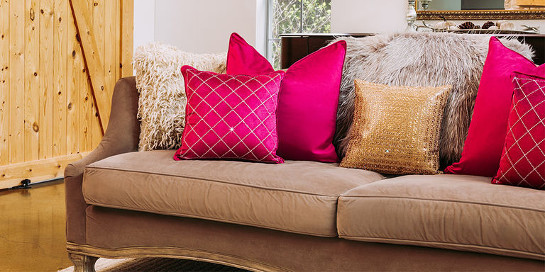 Layered&amp;&#x23;x20&#x3B;decorative&amp;&#x23;x20&#x3B;pillows&amp;&#x23;x20&#x3B;featuring&amp;&#x23;x20&#x3B;gold&amp;&#x23;x20&#x3B;beaded,&amp;&#x23;x20&#x3B;red&amp;&#x23;x20&#x3B;velvet,&amp;&#x23;x20&#x3B;and&amp;&#x23;x20&#x3B;patterned&amp;&#x23;x20&#x3B;designs&amp;&#x23;x20&#x3B;on&amp;&#x23;x20&#x3B;taupe&amp;&#x23;x20&#x3B;sofa
