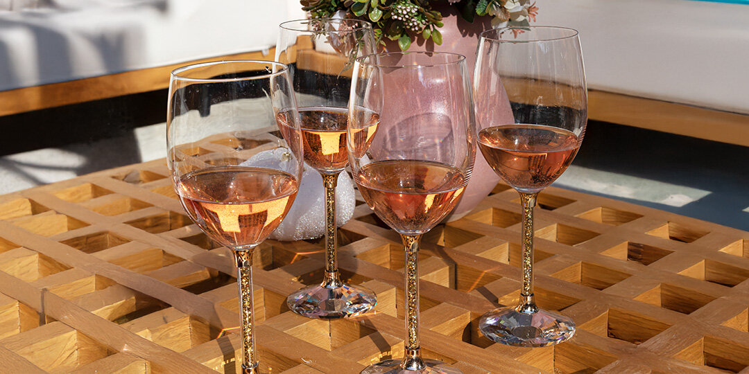 Collection&amp;&#x23;x20&#x3B;of&amp;&#x23;x20&#x3B;wine&amp;&#x23;x20&#x3B;glasses&amp;&#x23;x20&#x3B;with&amp;&#x23;x20&#x3B;rhinestone&amp;&#x23;x20&#x3B;filled&amp;&#x23;x20&#x3B;stems&amp;&#x23;x20&#x3B;filled&amp;&#x23;x20&#x3B;with&amp;&#x23;x20&#x3B;ros&amp;&#x23;xE9&#x3B;&amp;&#x23;x20&#x3B;wine,&amp;&#x23;x20&#x3B;arranged&amp;&#x23;x20&#x3B;on&amp;&#x23;x20&#x3B;a&amp;&#x23;x20&#x3B;geometric&amp;&#x23;x20&#x3B;wooden&amp;&#x23;x20&#x3B;checkerboard&amp;&#x23;x20&#x3B;surface.&amp;&#x23;x20&#x3B;Various&amp;&#x23;x20&#x3B;glass&amp;&#x23;x20&#x3B;sizes&amp;&#x23;x20&#x3B;including&amp;&#x23;x20&#x3B;champagne&amp;&#x23;x20&#x3B;flutes&amp;&#x23;x20&#x3B;and&amp;&#x23;x20&#x3B;wine&amp;&#x23;x20&#x3B;glasses&amp;&#x23;x20&#x3B;are&amp;&#x23;x20&#x3B;displayed,&amp;&#x23;x20&#x3B;with&amp;&#x23;x20&#x3B;small&amp;&#x23;x20&#x3B;potted&amp;&#x23;x20&#x3B;succulents&amp;&#x23;x20&#x3B;visible&amp;&#x23;x20&#x3B;in&amp;&#x23;x20&#x3B;the&amp;&#x23;x20&#x3B;background.